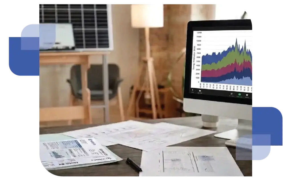 A workspace featuring printed data reports on a desk, video call on a computer screen showing a colorful stacked area chart, and a solar panel visible in the background.