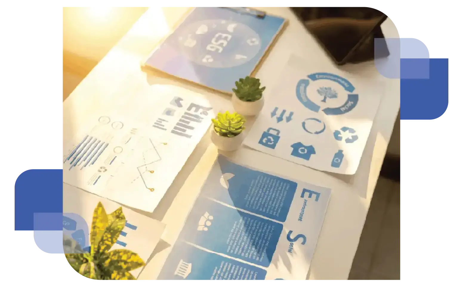 Overhead shot of a workspace with printed sustainability reports, a smartphone, and a tablet showing a dashboard with the text "ESG" and leaf icons, representing environmental data management.